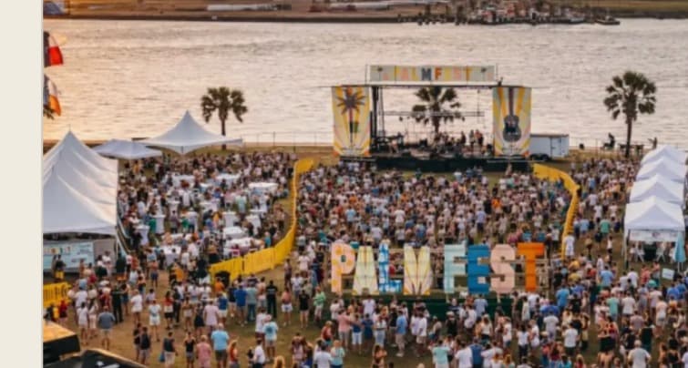 PALMFEST main stage with giant letter installation, festival crowd, palm trees, and the Gulf in the background